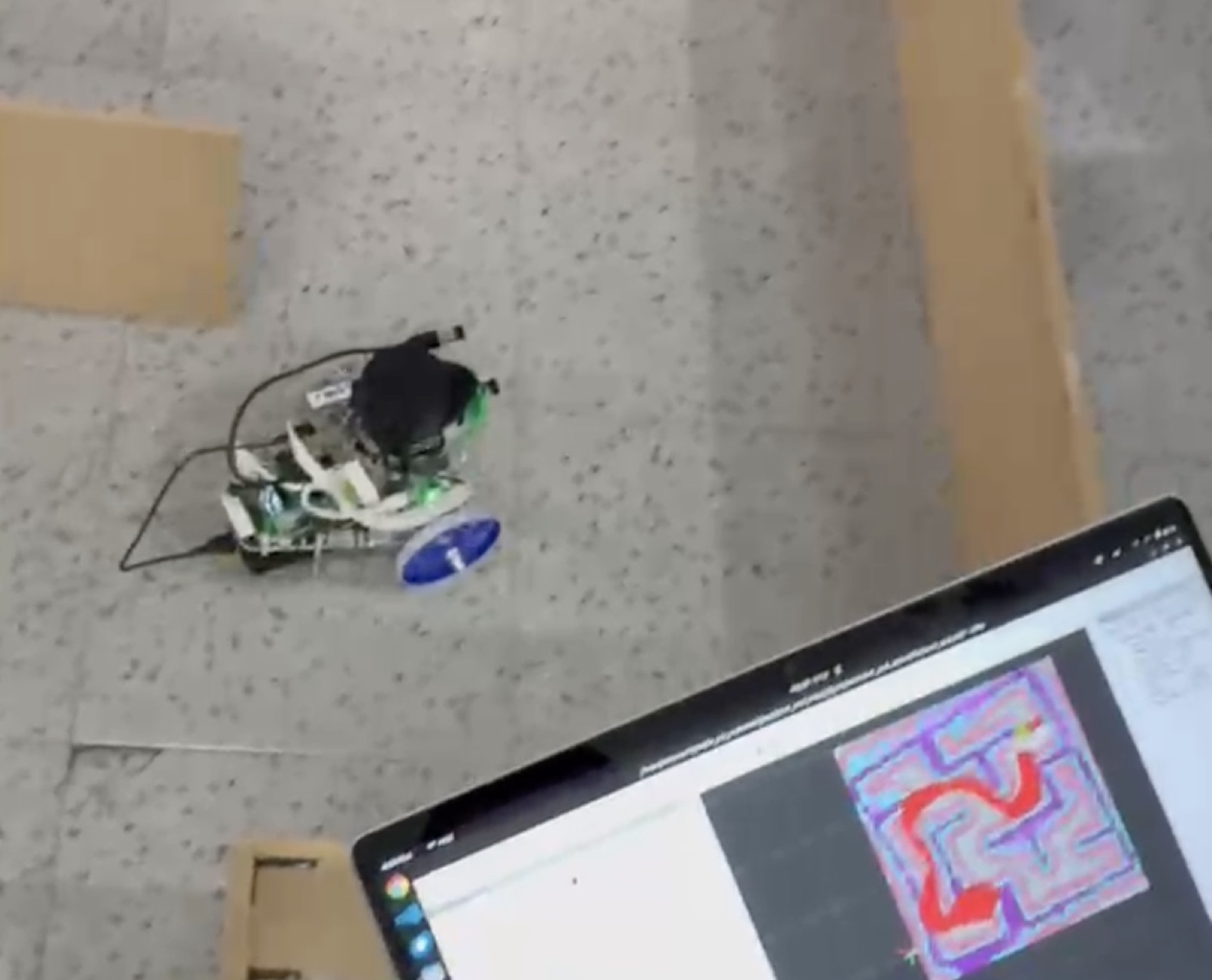 MCR2 Puzzlebot navigating a taped maze while a laptop displays its colored route and map.